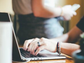 Obrazek przedstawia osobę piszącą na laptopie