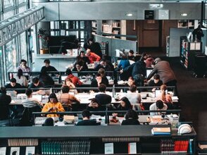 Grafika przedstawia bibliotekę pełną studentów.
