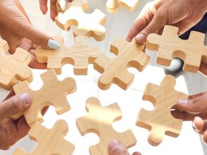 Zdjęcie przedstawia ręce składające puzzle.