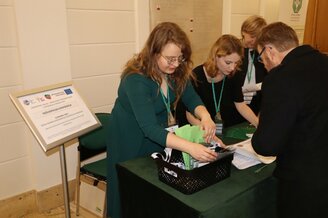 Zdjęcie przedstawia uczestników konferencji podczas rejestracji