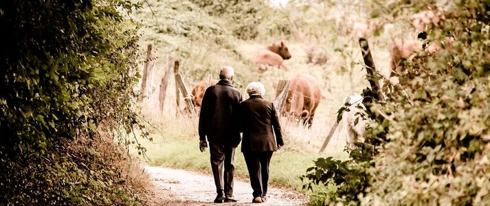 Obrazek przedstawia 2 seniorów kobietę i mężycznę spacerujących na wsi.