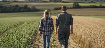 Zdjęcie przedstawia parę młodych rolników idących po polu