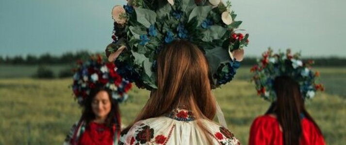 Zdjęcie przedstawia 3 kobiety w strojach ludowych, będące na polu uprawnym (zboże).