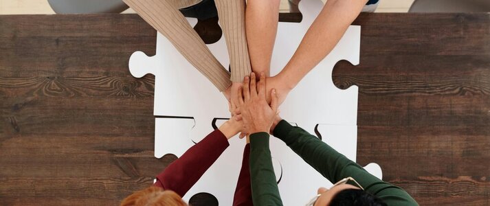 Zdjęcie przedstawia dłonie 4 osób wskazujące na współpracę