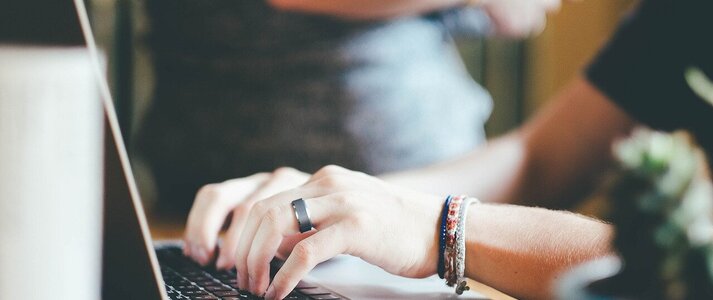 Obrazek przedstawia osobę piszącą na laptopie