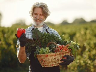 Zdjecie przedstawia rolnika z koszem warzyw