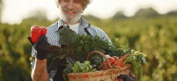 Zdjecie przedstawia rolnika z koszem warzyw