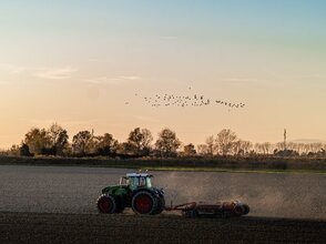 Zdjęcie przedstawia traktor jadący na polu