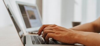 Obraz przedstawia osobę pracującą na laptopie.