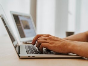Obraz przedstawia osobę pracującą na laptopie.