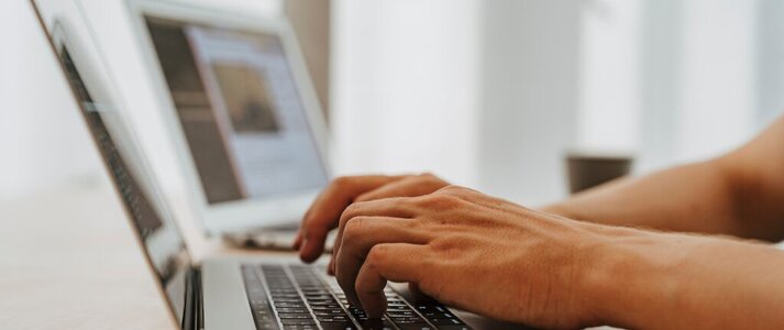 Obraz przedstawia osobę pracującą na laptopie.