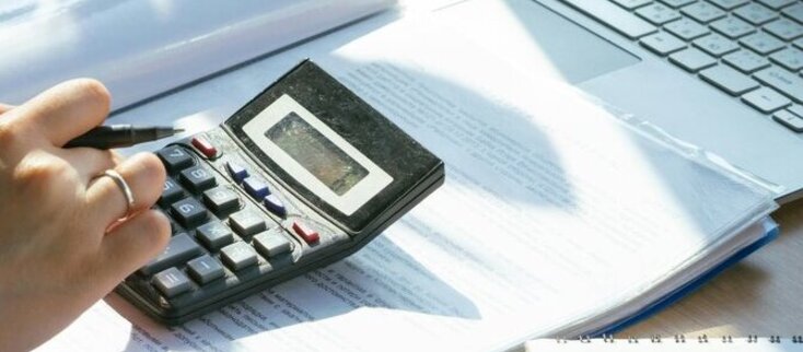 Zdjęcie przedstawia kobietę liczącą na kalkulatorze