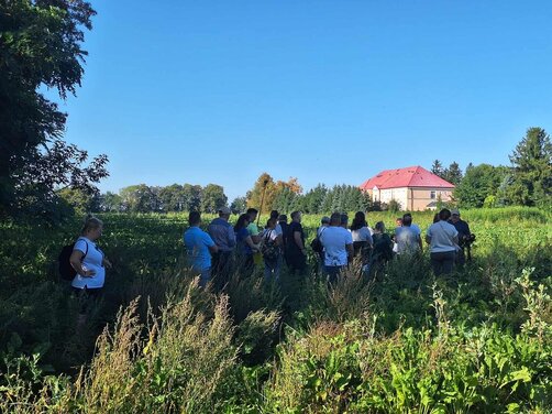 Zdjęcie przedstawia uczestników konferencji podczas wizyty studyjnej w gospodarstwie rolnym.