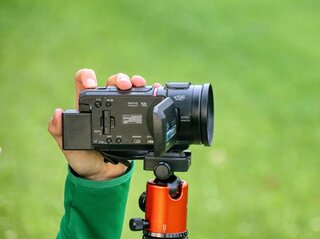 Zdjęcie przedstawia rękę trzymającą kamerę