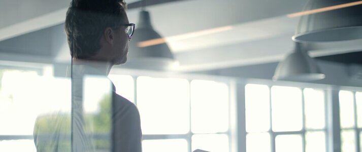 Zdjęcie przedstawia mężczyzną z laptopem, widocznego od tyłu.