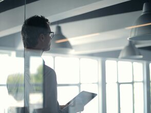 Zdjęcie przedstawia mężczyzną z laptopem, widocznego od tyłu