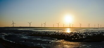 Zdjęcie przedstawia wiatraki o zachodzie słońca