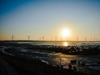 Zdjęcie przedstawia wiatraki o zachodzie słońca