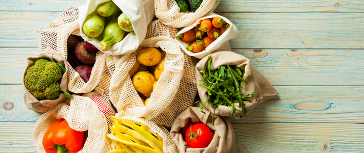 fresh vegetables in eco cotton bags on table top view