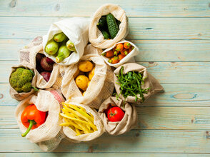 fresh vegetables in eco cotton bags on table top view