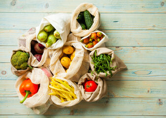 fresh vegetables in eco cotton bags on table top view